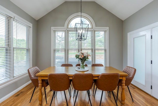 dining space with lofted ceiling, light wood-type flooring, and a notable chandelier