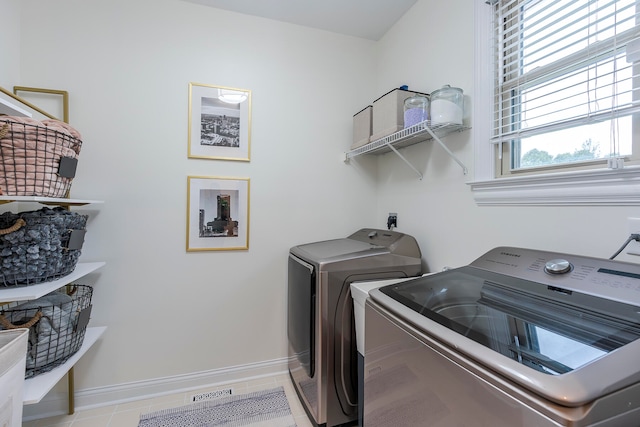 clothes washing area featuring light tile patterned floors and washer and dryer