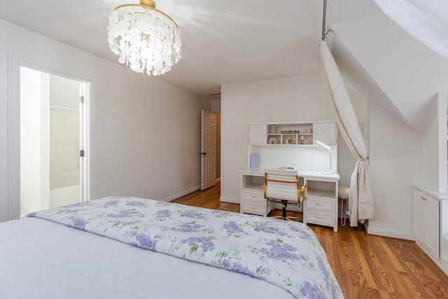 bedroom featuring connected bathroom, a chandelier, and light hardwood / wood-style floors