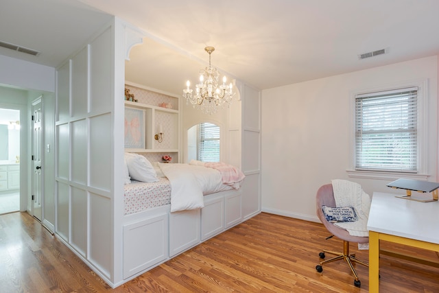 bedroom with a notable chandelier and light wood-type flooring