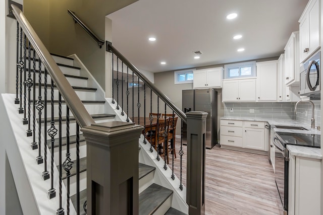 staircase featuring wood-type flooring and sink