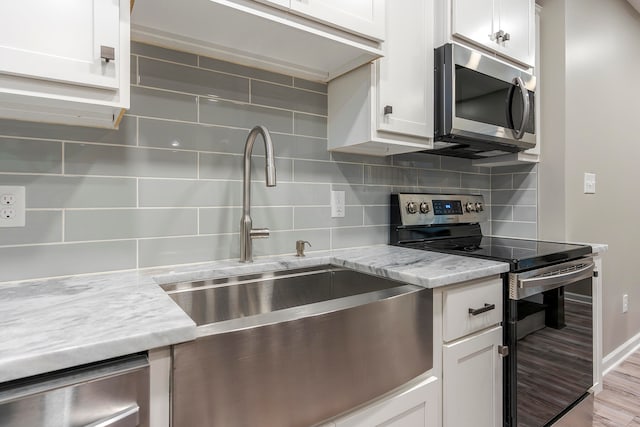 kitchen with light hardwood / wood-style floors, white cabinetry, and stainless steel appliances