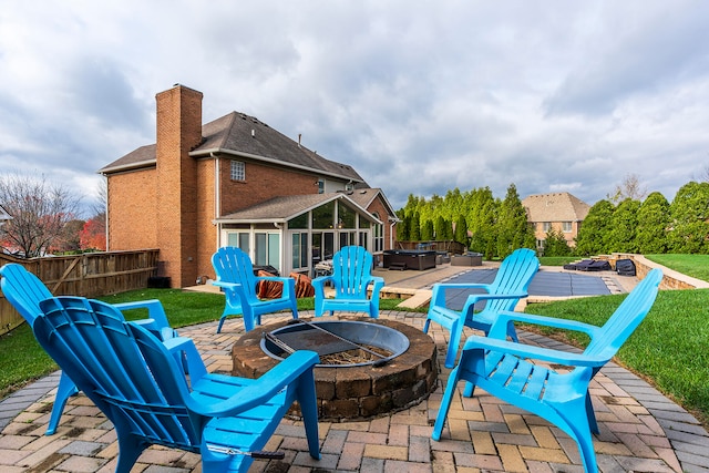 view of patio featuring a fire pit, a sunroom, and a hot tub