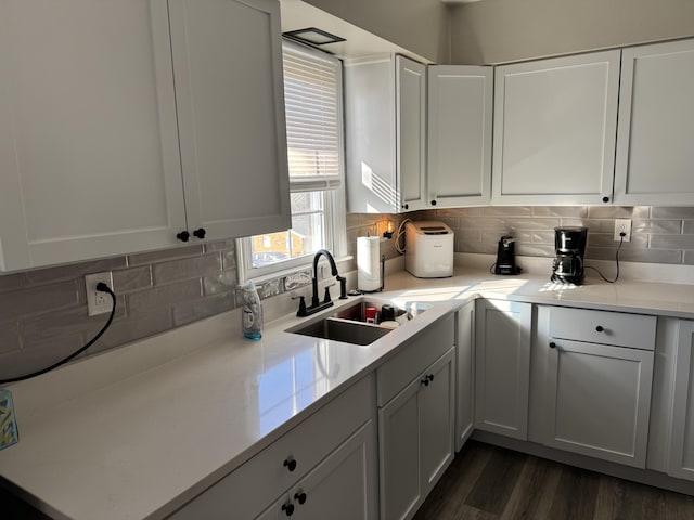 kitchen featuring a sink, tasteful backsplash, dark wood-style floors, white cabinets, and light countertops