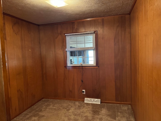 unfurnished room with a textured ceiling, carpet floors, and wooden walls