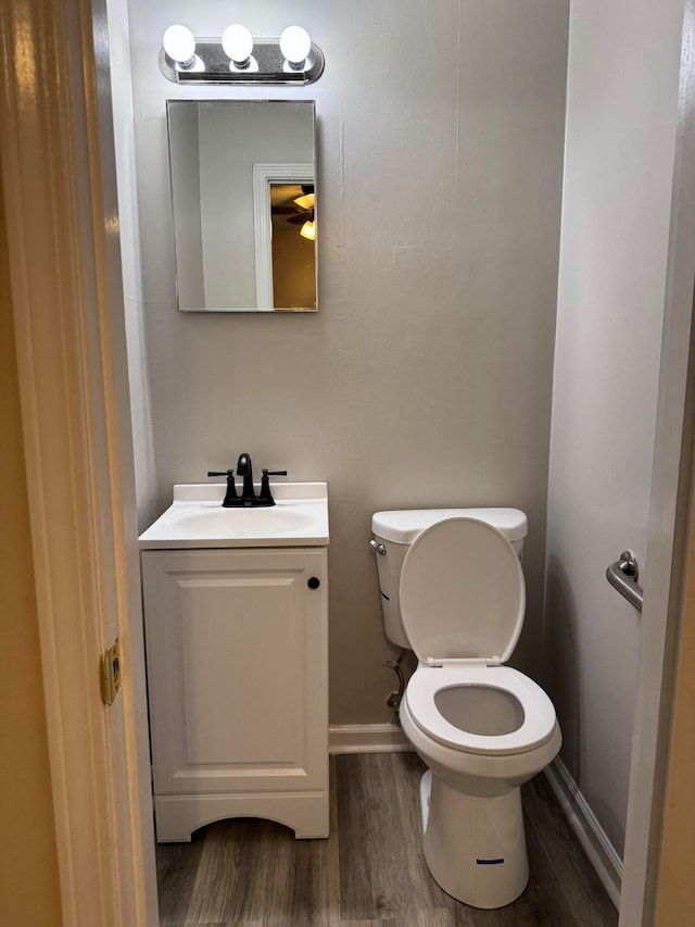 bathroom with toilet, vanity, and hardwood / wood-style flooring