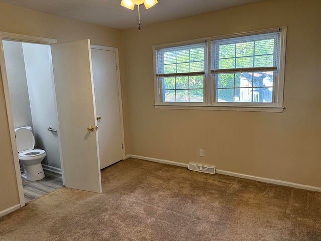 unfurnished bedroom with connected bathroom and light colored carpet