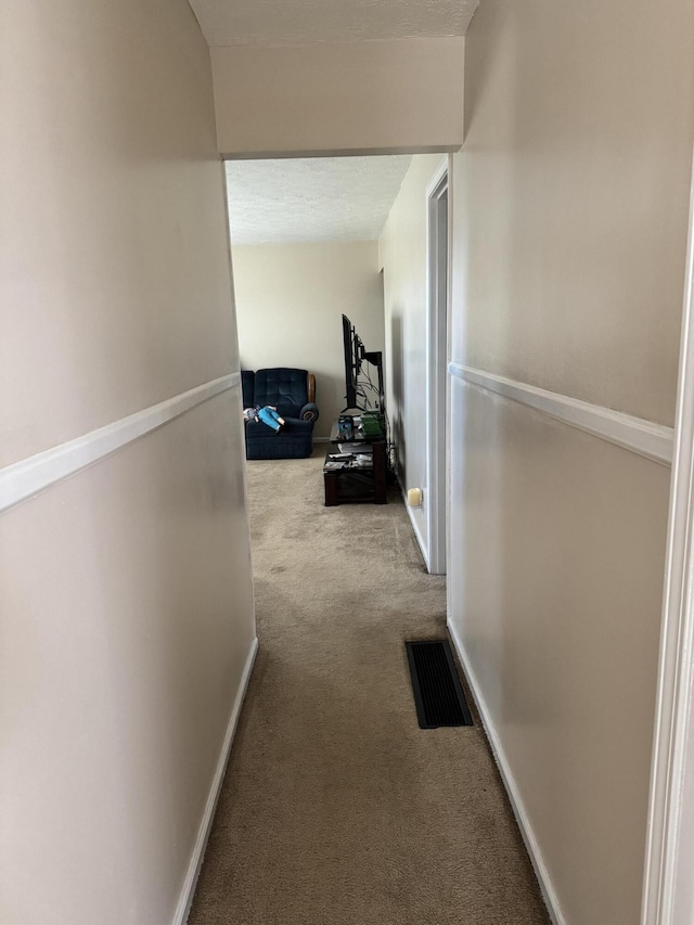 corridor featuring carpet flooring, baseboards, and visible vents