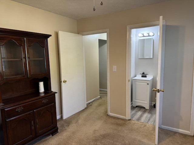 bedroom with a sink, baseboards, and light carpet