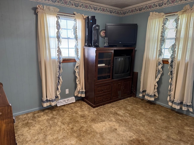 carpeted bedroom with wooden walls and ornamental molding