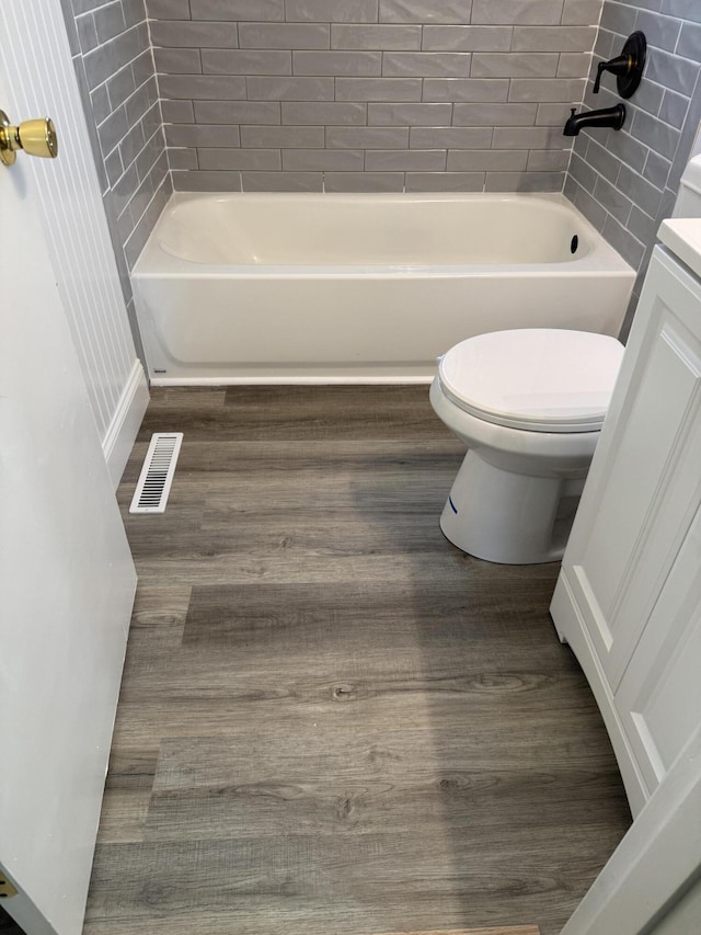 full bathroom with visible vents, toilet, wood finished floors, and  shower combination