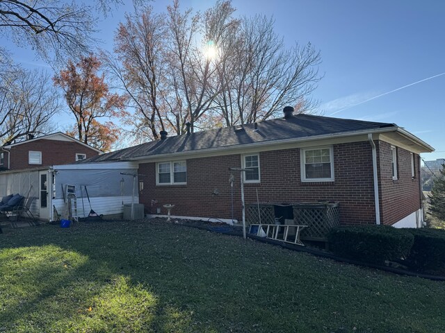 back of property with brick siding, cooling unit, and a yard