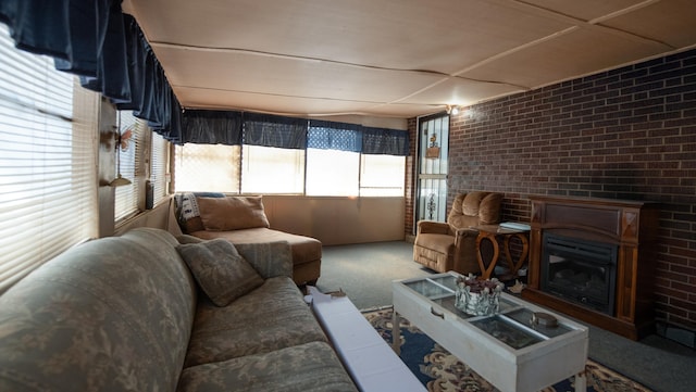 carpeted living area featuring a glass covered fireplace and brick wall