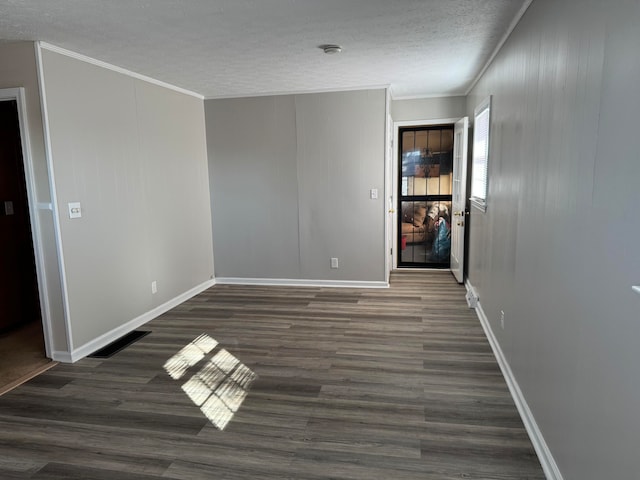 unfurnished room featuring a textured ceiling, ornamental molding, and dark wood-type flooring