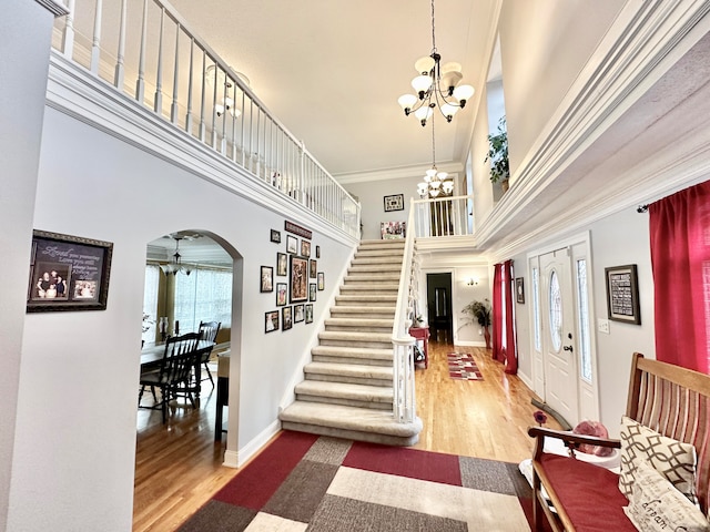 entryway featuring a chandelier, a high ceiling, crown molding, and hardwood / wood-style floors