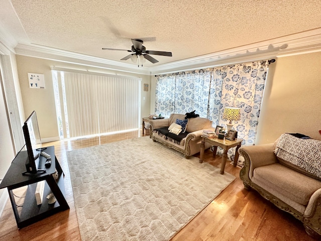 living area featuring ceiling fan, hardwood / wood-style floors, a textured ceiling, and ornamental molding