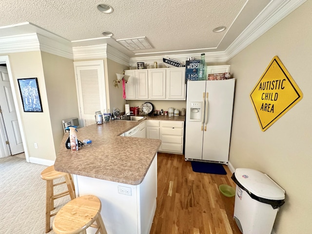 kitchen featuring white refrigerator with ice dispenser, white cabinetry, ornamental molding, and sink