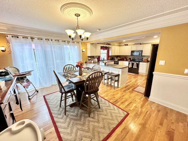 dining room with a chandelier, a textured ceiling, light hardwood / wood-style floors, and crown molding