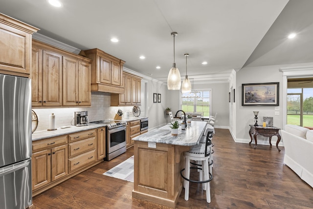 kitchen with stainless steel appliances, sink, decorative light fixtures, a center island with sink, and dark hardwood / wood-style floors