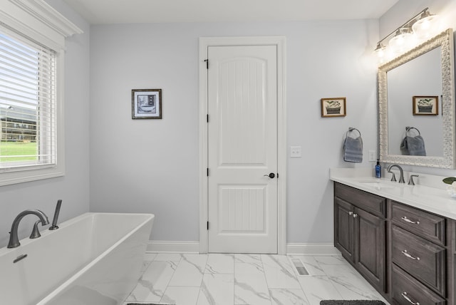 bathroom featuring plenty of natural light, a washtub, and vanity