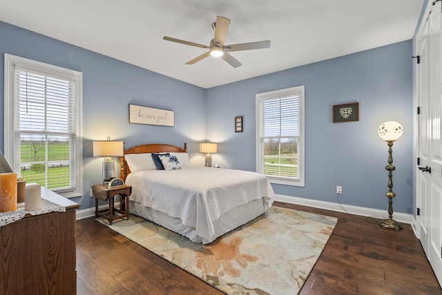 bedroom with ceiling fan, dark wood-type flooring, and multiple windows