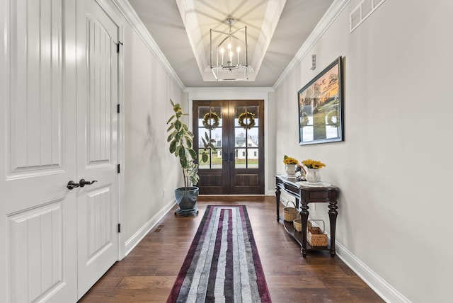 entryway featuring french doors, crown molding, dark hardwood / wood-style floors, a tray ceiling, and a chandelier