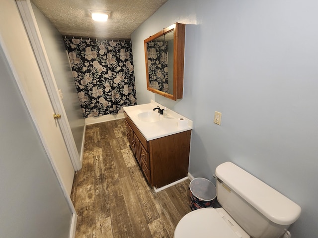 bathroom featuring hardwood / wood-style flooring, vanity, toilet, and a textured ceiling