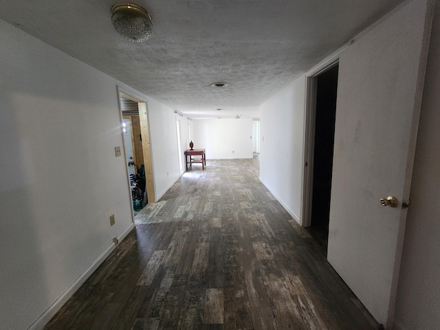 hallway featuring a textured ceiling and dark hardwood / wood-style flooring