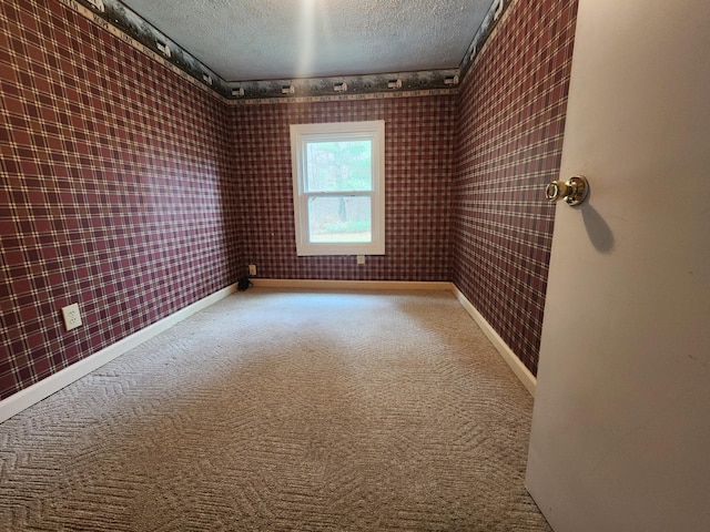 empty room with carpet flooring, brick wall, and a textured ceiling