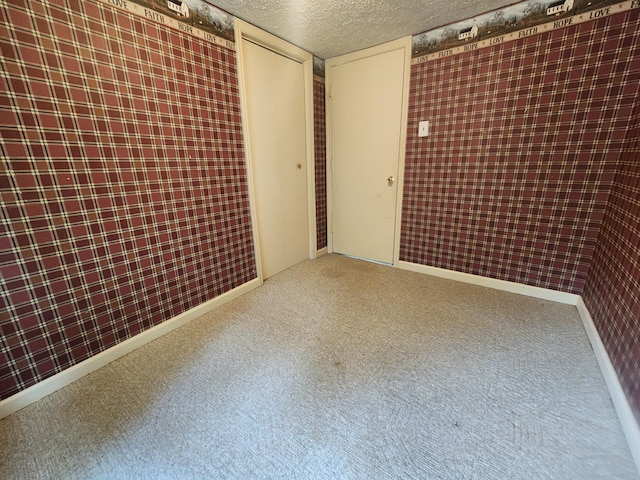 unfurnished room with carpet and a textured ceiling