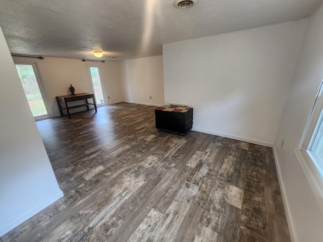 empty room featuring a textured ceiling and dark wood-type flooring