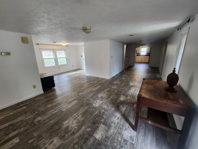 unfurnished living room featuring dark hardwood / wood-style flooring and a textured ceiling