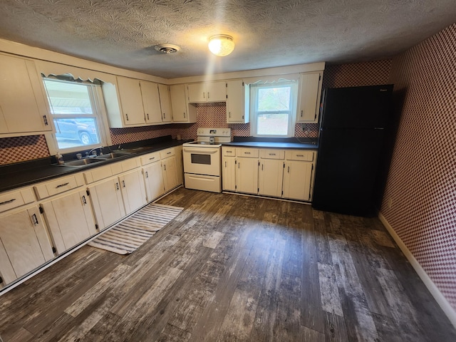 kitchen with dark hardwood / wood-style floors, backsplash, cream cabinets, electric stove, and black refrigerator