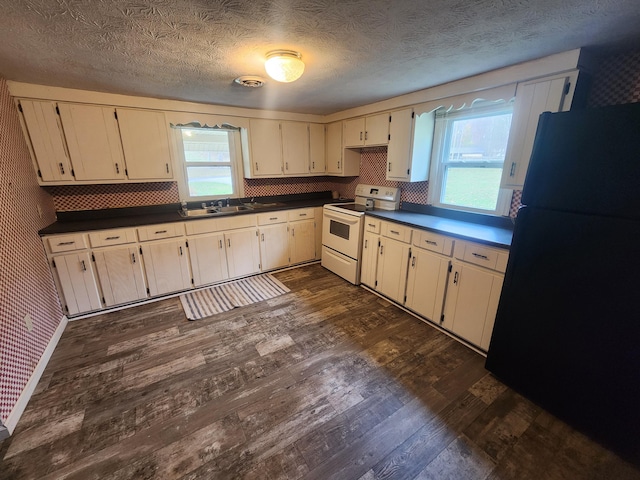 kitchen featuring range with electric cooktop, black refrigerator, dark wood-type flooring, and plenty of natural light