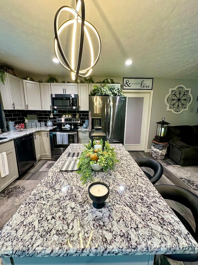 kitchen featuring white cabinets, light wood-type flooring, appliances with stainless steel finishes, tasteful backsplash, and a kitchen island