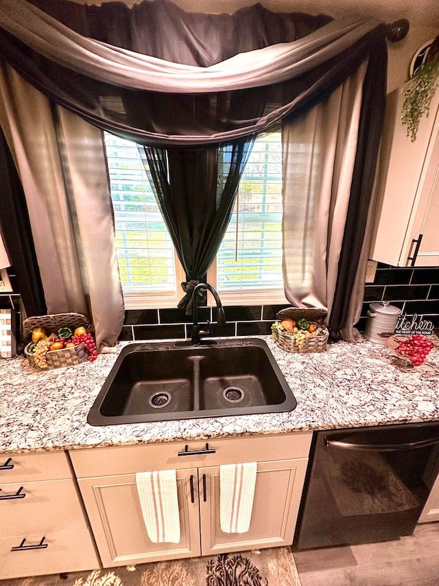 kitchen with sink, light stone countertops, black dishwasher, and tasteful backsplash