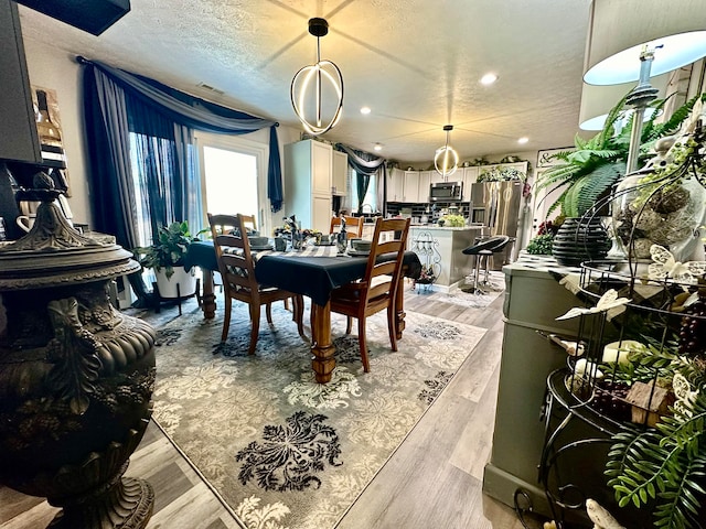 dining area with light hardwood / wood-style flooring and a textured ceiling