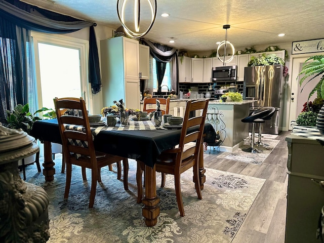 dining room featuring a wealth of natural light, light hardwood / wood-style flooring, and a textured ceiling