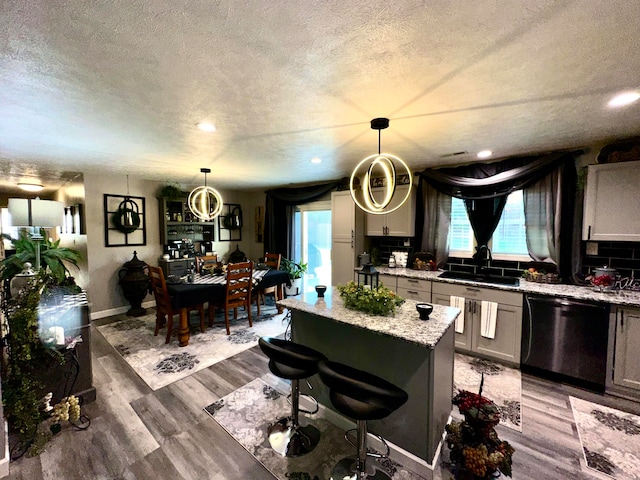 kitchen featuring sink, wood-type flooring, decorative light fixtures, and black dishwasher