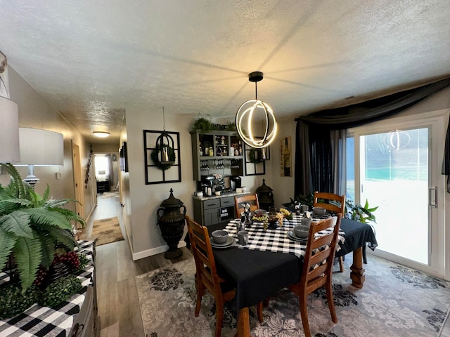 dining area with indoor bar, a textured ceiling, and light hardwood / wood-style flooring