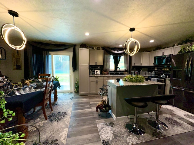 kitchen with a wealth of natural light, hanging light fixtures, and black appliances