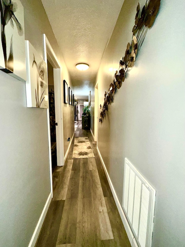 hall with dark hardwood / wood-style flooring and a textured ceiling