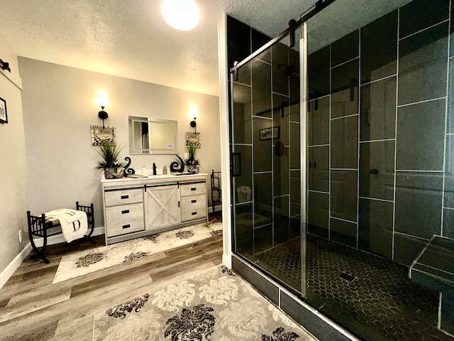 bathroom featuring a shower with door, vanity, a textured ceiling, and hardwood / wood-style flooring