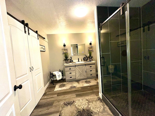 bathroom with hardwood / wood-style flooring, vanity, walk in shower, and a textured ceiling