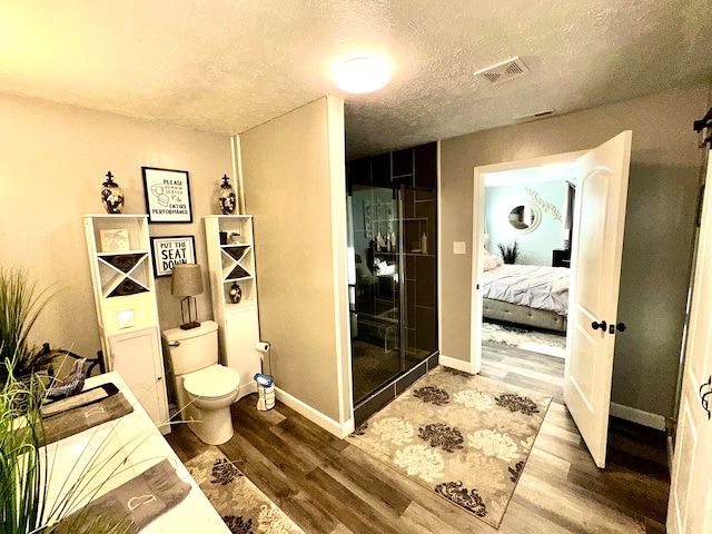 bathroom featuring wood-type flooring, a textured ceiling, and toilet