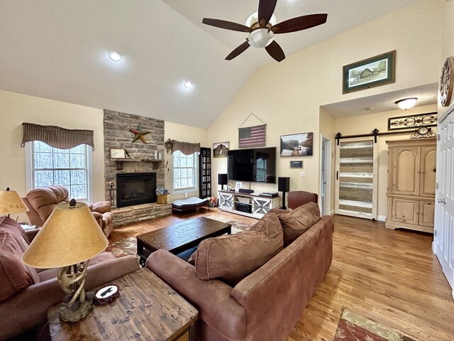 living room featuring hardwood / wood-style flooring, ceiling fan, a fireplace, and high vaulted ceiling