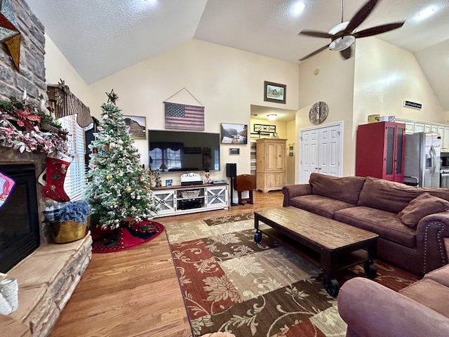 living room with hardwood / wood-style flooring, ceiling fan, a textured ceiling, and high vaulted ceiling