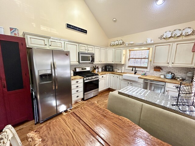 kitchen with backsplash, stainless steel appliances, butcher block countertops, and hardwood / wood-style flooring