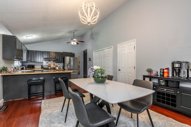 dining room featuring ceiling fan with notable chandelier, sink, high vaulted ceiling, and dark hardwood / wood-style floors