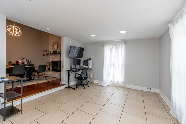 office area with a fireplace, light tile patterned flooring, and an inviting chandelier